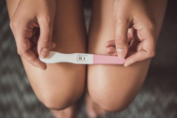Woman Holding Pregnancy Test on Knees